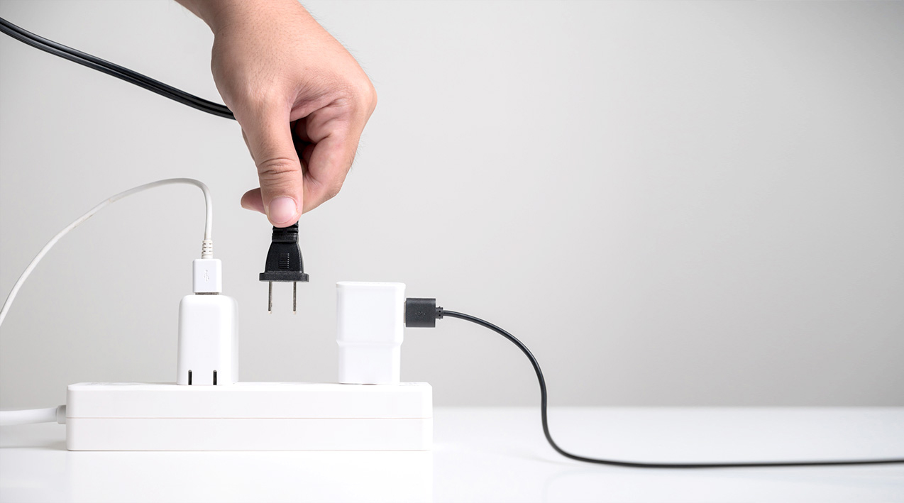 A hand plugging a cord into a smart power bar.