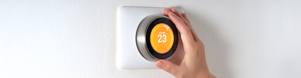 Hand adjusting a smart thermostat to 23 degrees Celsius