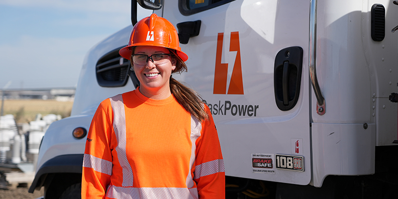 Ashely who is one of our Powerline Technicians is standing in front of a SaskPower truck