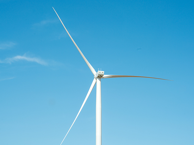 The top of a wind turbine in front of a blue sky. 